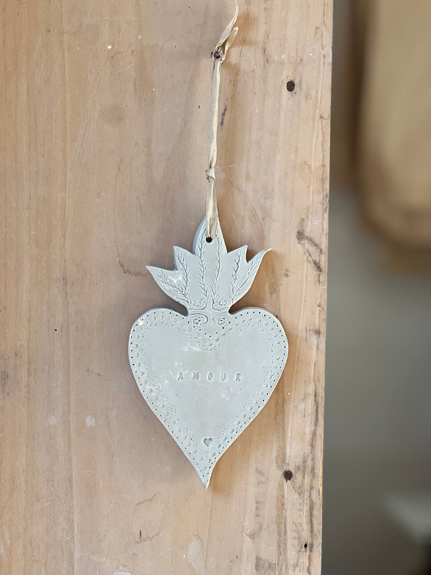 coeur réalisé à la main en poterie artisanale il est martelé et contient l'inscription amour dessus