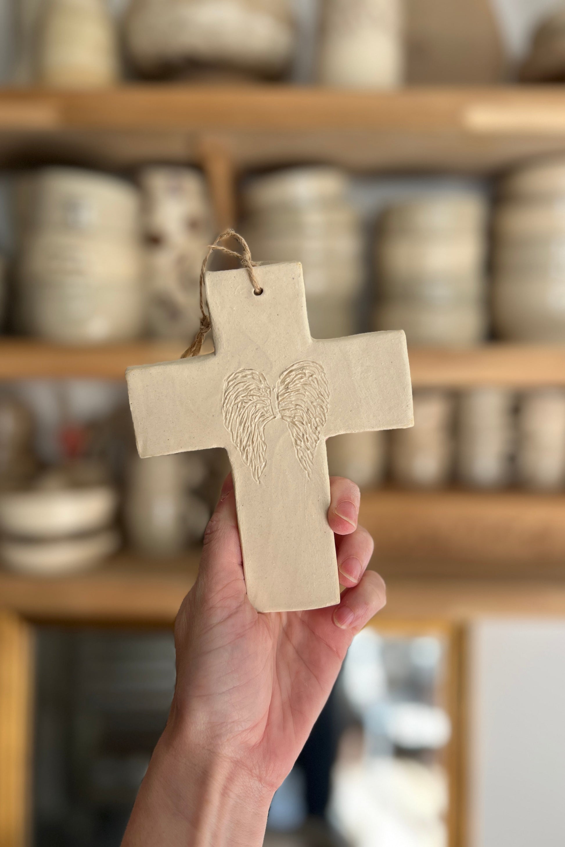 croix en terre non émaillée avec ailes d'ange faite a la main dans atelier de poterie à Montpellier 