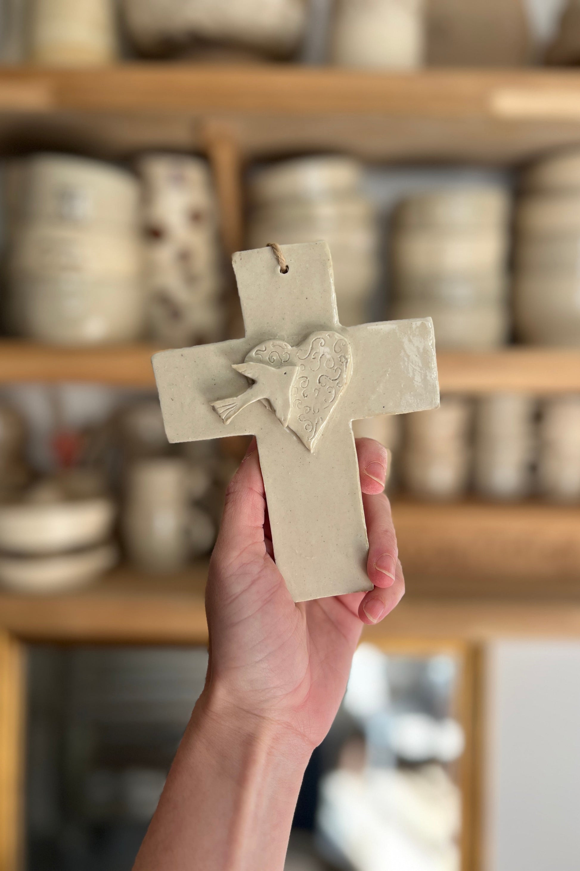 croix en céramique représentant un coeur et un oiseau faite a la main en ceramique dans un atelier de poterie à Montpellier