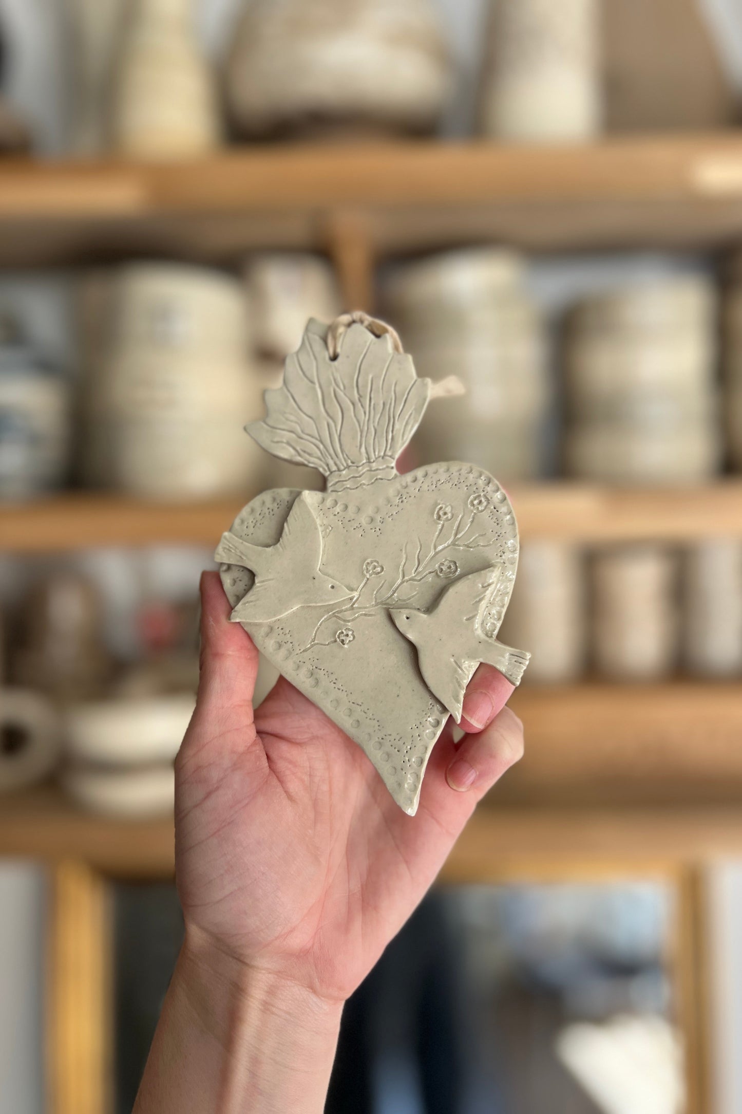 ex voto ou coeur sacré artisanal entièrement réalisé à la main en argile en grès il est représenté deux oiseaux en diagonale séparés par un feuillage pièce unique
