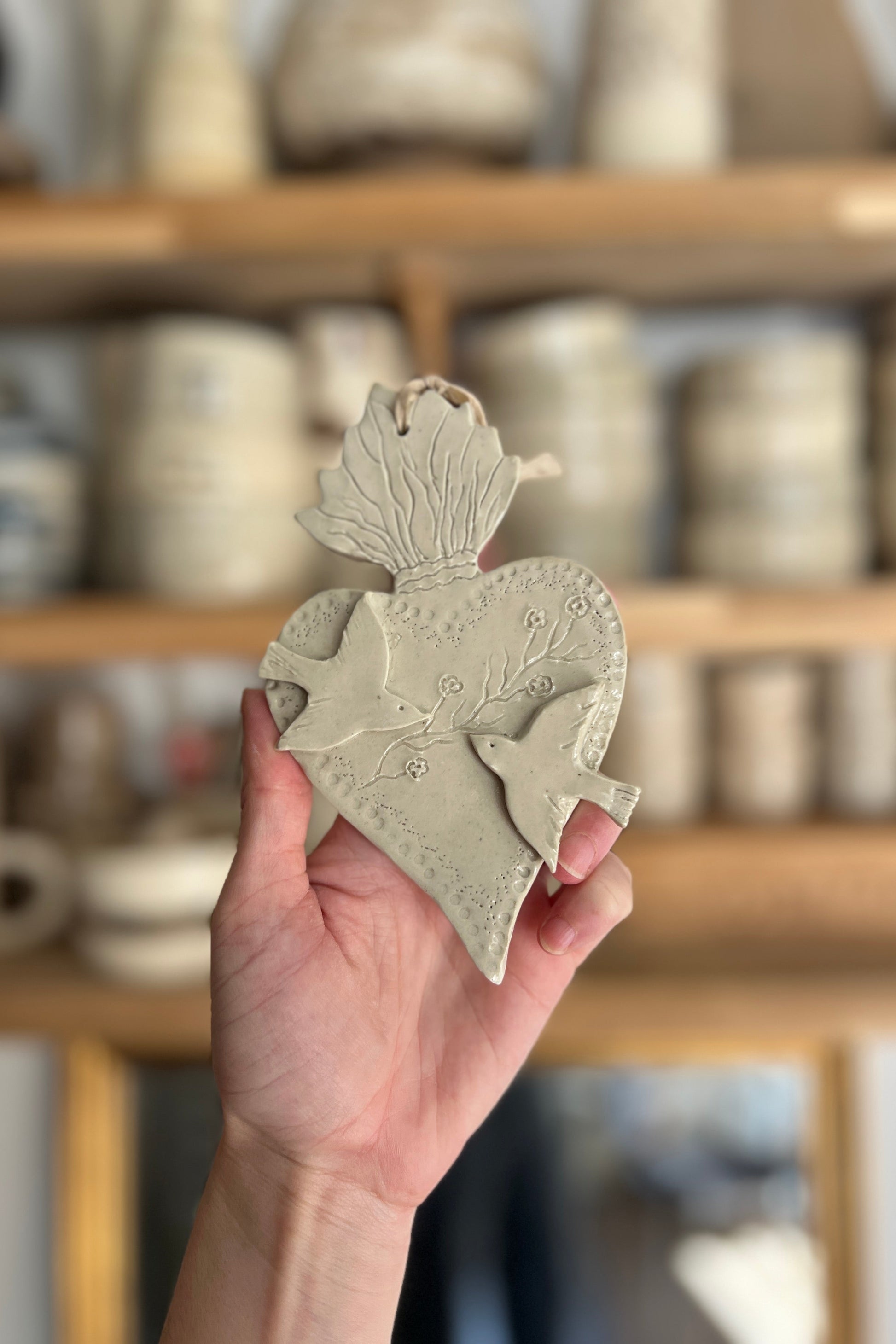ex voto ou coeur sacré artisanal entièrement réalisé à la main en argile en grès il est représenté deux oiseaux en diagonale séparés par un feuillage pièce unique