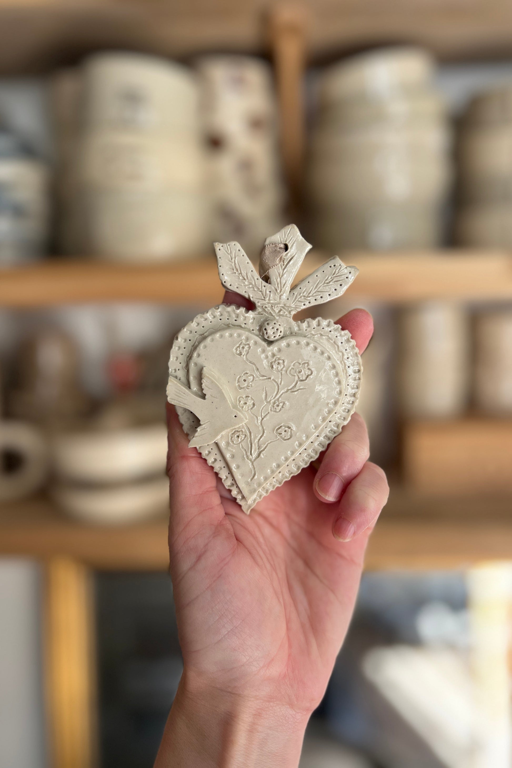 petit coeur sacré ou ex voto avec un oiseau et des détails martelés sur le coeur réalisé a la main dans un atelier artisanal de poterie près de Montpellier à baillargues
